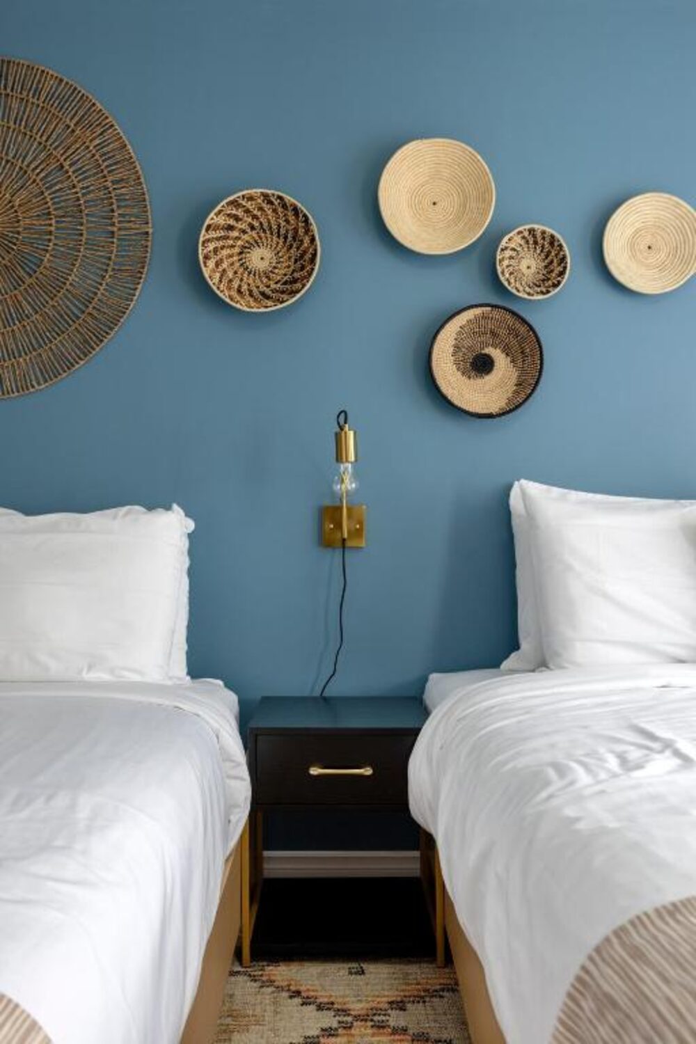 A guest room with two beds and a blue accent wall